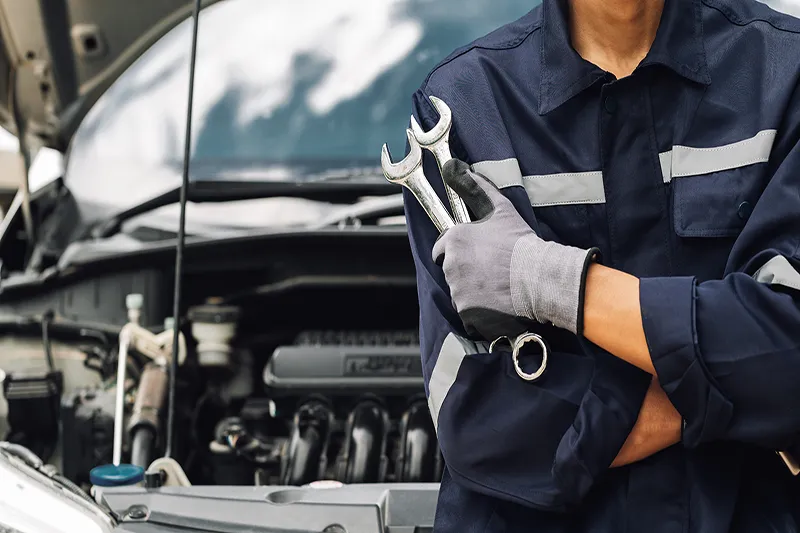 Automechaniker, der in einer Werkstatt mit einem Schraubenschlüssel hantiert.